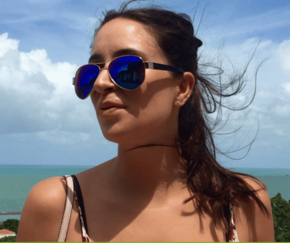 Young girl wearing blue sunglasses in front of the ocean