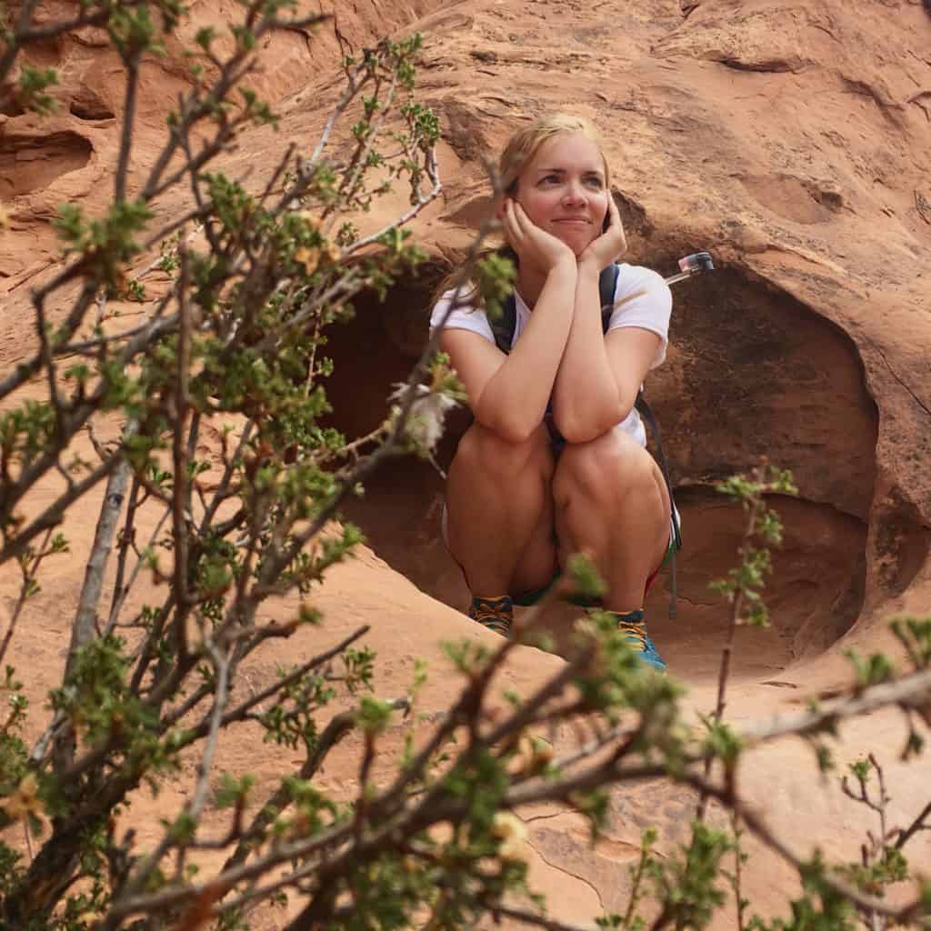 A young hiker kneeling in the crevice of a rock.